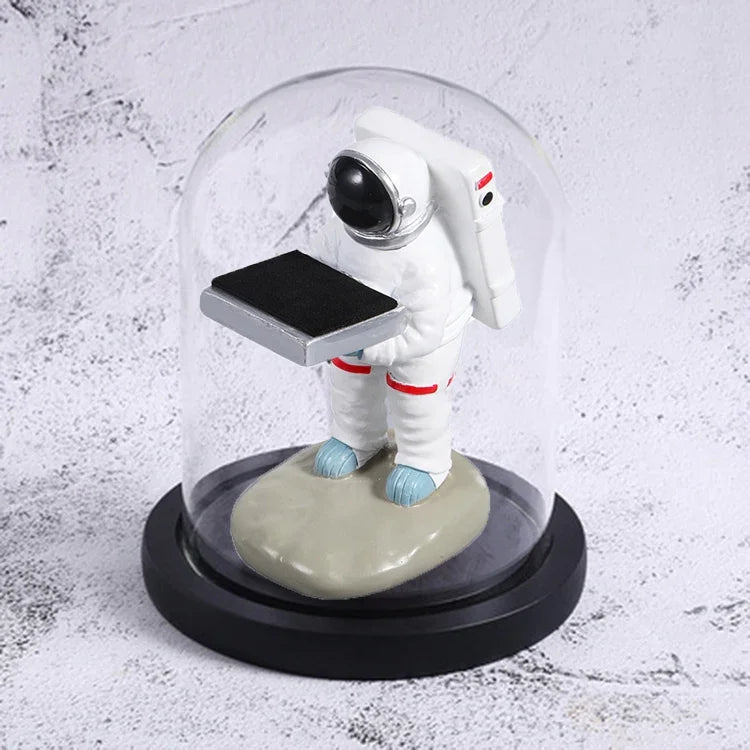 Decorative watch display stand with small astronaut figurine under glass dome for stylish storage.