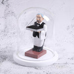 Decorative watch display stand featuring a vintage butler figurine under a glass dome with a white base.